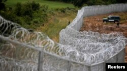 FILE - Bulgarian border police stand near a barbed wire fence on the Bulgarian-Turkish border, July 17, 2014. 