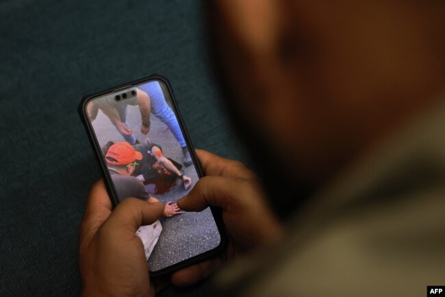 Seorang pria menonton video yang dipublikasikan di media sosial, yang memperlihatkan seorang pria terluka setelah ledakan menghantam beberapa lokasi di kubu Hizbullah di sekitar Lebanon, 17 September 2024. (JOSEPH EID / AFP)
