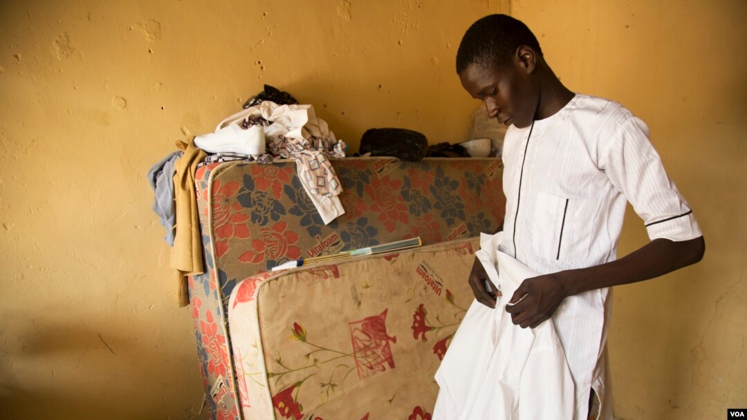 Abdulkadir Abdullahi arranges his school uniform in Maiduguri, Nigeria, October 2016. (C. Oduah/VOA)