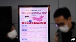 FILE - A poster warning about coronavirus is seen as passengers wear masks in a departure lobby at Incheon International Airport in Incheon, South Korea, Jan. 27, 2020. 