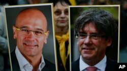 Una mujer sostiene dos fotos, una del ex miembro del gabinete catalán, Raum Romeva y el ex líder de la Generalitat, Carles Puigdemont, durante una protesta en apoyo a los llamados presos políticos. 