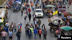 Rice farmers walk between their tractors on a main highway where they spent a night in Ayutthaya. Thai farmers called off a tractor drive to Bangkok's main airport to protest against not being paid under a rice subsidy scheme after an assurance they would