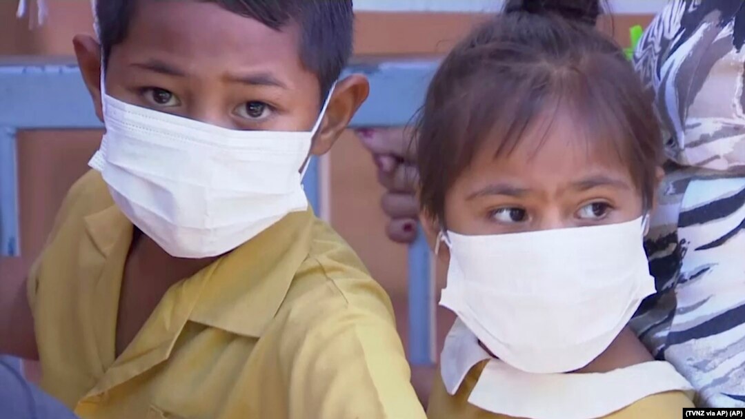 In this November 2019, image from video, masked children wait to get vaccinated against measles at a health clinic in Apia, Samoa.