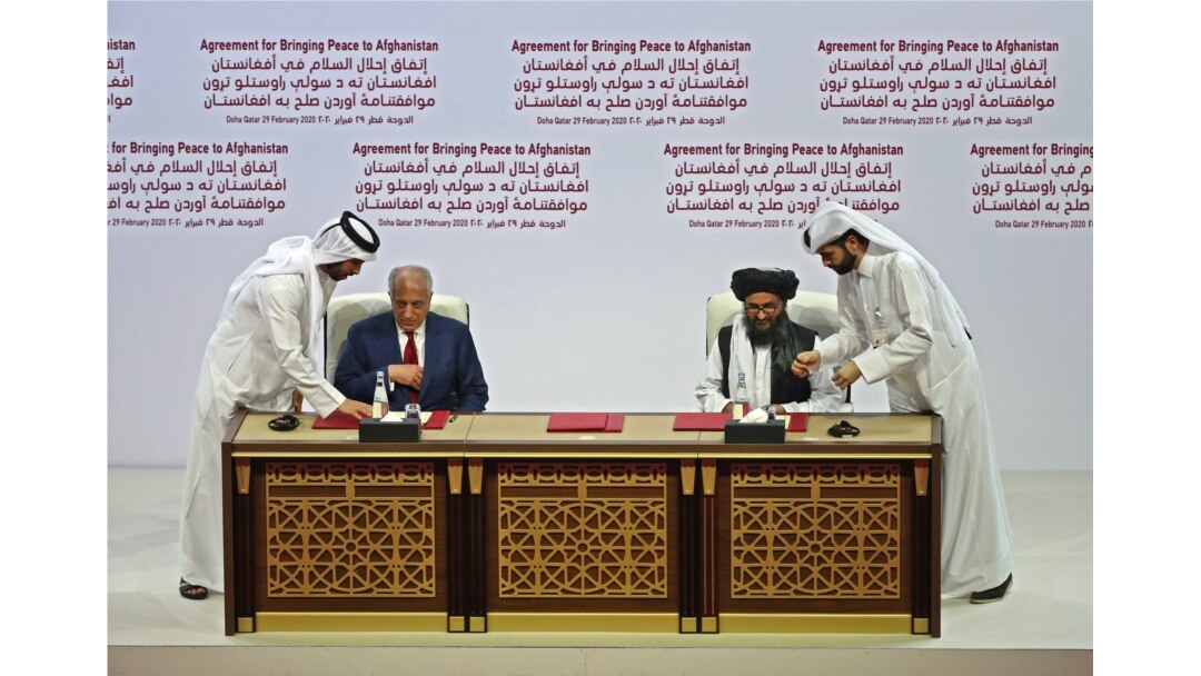 FILE - U.S. Special Representative for Afghanistan Reconciliation Zalmay Khalilzad and Taliban deputy chief for political affairs Mullah Abdul Ghani Baradar sign the U.S.-Taliban peace agreement during a ceremony in Doha, Feb. 29, 2020.