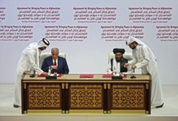 FILE - U.S. Special Representative for Afghanistan Reconciliation Zalmay Khalilzad and Taliban deputy chief for political affairs Mullah Abdul Ghani Baradar sign the U.S.-Taliban peace agreement during a ceremony in Doha, Feb. 29, 2020.