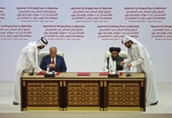 FILE - U.S. Special Representative for Afghanistan Reconciliation Zalmay Khalilzad and Taliban deputy chief for political affairs Mullah Abdul Ghani Baradar sign the U.S.-Taliban peace agreement in the Qatari capital, Doha, Feb. 29, 2020.