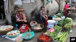 FILE - A woman sells vegetables at an outdoor market in Hanoi, Vietnam, Feb. 21, 2019.