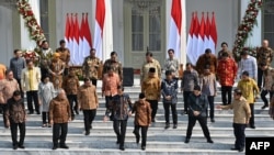 Presiden Joko Widodo (tengah kiri) dan Wakil Presiden Ma'ruf Amin (tengah kanan) bergandengan sebelum sesi foto dengan anggota kabinet baru di tangga Istana Merdeka, 23 Oktober 2019. (Foto: AFP)