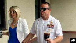FILE - Navy SEAL Edward (Eddie) Gallagher, right, walks with his wife, Andrea Gallagher, as they arrive at a military court on Naval Base San Diego, in San Diego, California, June 26, 2019. 