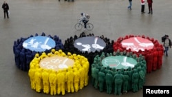 FILE - Olympic rings are displayed in Paris with images against restriction of speech and freedom of information, repression of demonstrations, discrimination based on sexual orientation and exploitation of migrants, part of a protest by human rights organizations a week before the Sochi Winter Olympics, Feb. 1, 2014. 