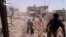 Citizen journalism image provided by Qusair Lens which has been authenticated based on its contents and other AP reporting, shows Syrians inspecting the rubble of damaged buildings due to government airstrikes, in Qusair, Homs province, Syria, May 18, 201