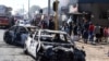 FILE: Pedestrians pass burnt out cars on the side of a street on the outskirts of Johannesburg, Monday Sept. 2, 2019.