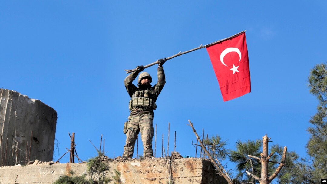 FILE - A soldier waves a Turkish flag as Turkish troops secure Bursayah hill, which separates the Kurdish-held enclave of Afrin from the Turkey-controlled town of Azaz, Syria, Jan. 28, 2018. 