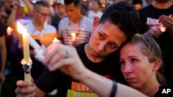 FILE - People hold candles during a vigil downtown for the victims of a mass shooting at the Pulse nightclub in Orlando, Florida, June 13, 2016.