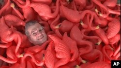 FILE - Don Featherstone, creator of the original plastic pink flamingo, is surrounded by the items at Union Products Inc. in Leominster, Mass. Featherstone died Monday at age 79 at an elder care facility in Fitchburg, Mass., according to his wife, Nancy.