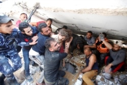 Rescuers carry Suzy Eshkuntana, 6, as they pull her from the rubble of a building at the site of Israeli air strikes, in Gaza City May 16, 2021. The pre-dawn Israeli strike killed her mother and all four of her siblings.
