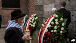 Un sobreviviente lleva una vela al Muro de la Muerte en el antiguo campo de concentración y exterminio nazi de Auschwitz-Birkenau, durante una ceremonia que conmemora el 80 aniversario de la liberación del campo, en Oswiecim, Polonia, el lunes 27 de enero de 2025. 