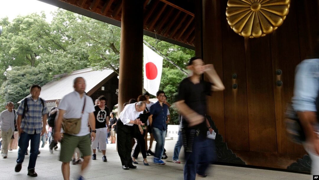 Seorang pengunjung membungkukkan badan untuk menghormati para pahlawan yang gugur dalam perang, saat pengunjung lainnya memasuki Tugu Yasukuni di Tokyo, Senin (15/8). 