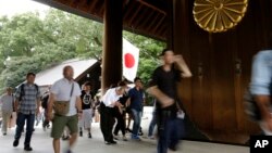 Seorang pengunjung membungkukkan badan untuk menghormati para pahlawan yang gugur dalam perang, saat pengunjung lainnya memasuki Tugu Yasukuni di Tokyo, Senin (15/8). 