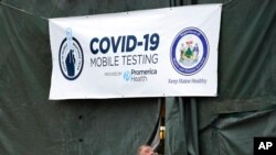 A member of the National Guard assisting at a COVID-19 mobile testing location looks out of a tent used for drive-thru tests, in Auburn, Maine, Dec. 1, 2020.