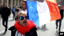 A far-right supporter marches next to French flag near the statue of Joan of Arc for his traditional march, May 1, 2017, in Paris. 