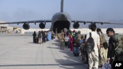 In this image provided by the U.S. Air Force, U.S. Air Force loadmasters and pilots assigned to the 816th Expeditionary Airlift Squadron, load people being evacuated from Afghanistan onto a U.S. Air Force C-17 Globemaster III at Hamid Karzai International