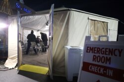 Clinicians evaluate a patient in a triage tent set up outside Providence St. Mary Medical Center amid a surge in COVID-19 patients in Southern California on Dec. 18, 2020, in Apple Valley, Calif.