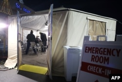 Clinicians evaluate a patient in a triage tent set up outside Providence St. Mary Medical Center amid a surge in COVID-19 patients in Southern California on Dec. 18, 2020, in Apple Valley, Calif.