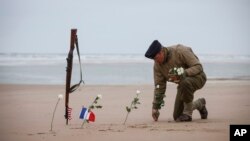 A World War II reenactor plants roses on Omaha Beach in Saint-Laurent-sur-Mer, Normandy, France, Tuesday, June 6, 2023. The D-Day invasion that helped change the course of World War II was unprecedented in scale and audacity. Nearly 160,000 Allied troops landed on the shores of Normandy at dawn on June 6, 1944. (AP Photo/Thomas Padilla)