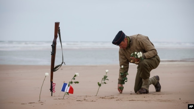 A World War II reenactor plants roses on Omaha Beach in Saint-Laurent-sur-Mer, Normandy, France, Tuesday, June 6, 2023. The D-Day invasion that helped change the course of World War II was unprecedented in scale and audacity. Nearly 160,000 Allied troops landed on the shores of Normandy at dawn on June 6, 1944. (AP Photo/Thomas Padilla)