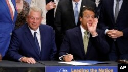 New York Gov. Andrew Cuomo, right, accompanied by former Vice President Al Gore, announces that he is signing the Climate Leadership and Community Protection Act, Thursday, July 18, 2019, at Fordham University in New York. 