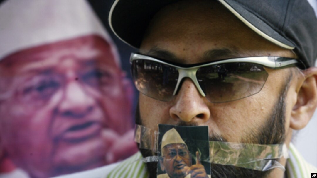 A supporter of veteran Indian social activist Anna Hazare is seen with a photo of Hazare over his mouth during a protest rally against corruption in the northern Indian city of Chandigarh Aug. 17, 2011.