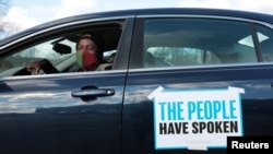 Tristan Taylor demonstrates in a car caravan as the Board of State Canvassers meet to certify the results of the election in Lansing, Michigan, Nov. 23, 2020. 