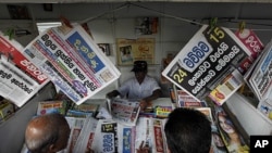 People stand in front of a newspaper stall, as headlines read, from left top, "Operation unsuccessful," "Might overrules right," and "Resolution against Sri Lanka passed," referring to the resolution passed by the U.N Human Rights Council in Geneva, in Co