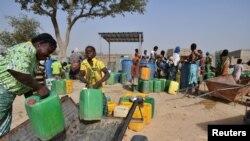 FILE - Displaced people, who fled from attacks of armed militants in town of Roffenaga, carry their jerrycans at the water point near UNHCR camp in Pissila, Burkina Faso, Jan. 24, 2020. 