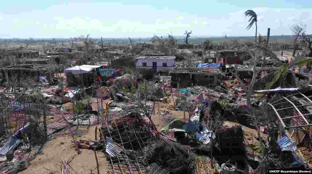 Pessoas de pé no meio de edifícios destruídos, árvores desenraizadas e destroços após o ciclone Chido ter atingido Moçambique, no distrito de Mecufi, província de Cabo Delgado, Moçambique, a 16 de dezembro de 2024, nesta captura de ecrã retirada de um vídeo de um drone.