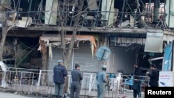 Afghan policemen inspect the site of a bomb attack in Kabul, Afghanistan, Jan.28, 2018. On Saturday, a car bomb ripped through a crowded area outside a government building, killing or wounding hundreds.