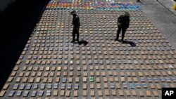 FILE - Police officers walk among packages of seized cocaine at the pacific port of Buenaventura, Colombia, Aug. 10, 2017. 