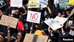 FILE - Women hold placards as they protest against gender-based violence, outside the Johannesburg Stock Exchange in Sandton, Johannesburg, South Africa, Sept. 13, 2019. 