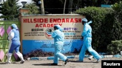 Officers from the office of government pathologist walk outside the Hillside Endarasha Academy, after a fatal fire killed and injured several pupils, in Kieni, Nyeri County, Kenya, Sept. 7, 2024. 