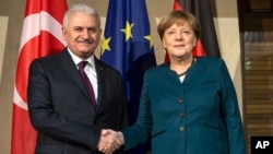 Le Premier ministre turc Binali Yildirim, à gauche, et la chancelière allemande Angela Merkel, à droite, se serrent la main lors la conférence de Munich sur la sécurité, en Allemagne, 18 février 2017.