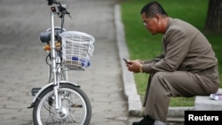 지난 10월 평양 시내에서 한 남성이 자전거를 세워놓고 휴대전화를 사용하고 있다. (자료사진)