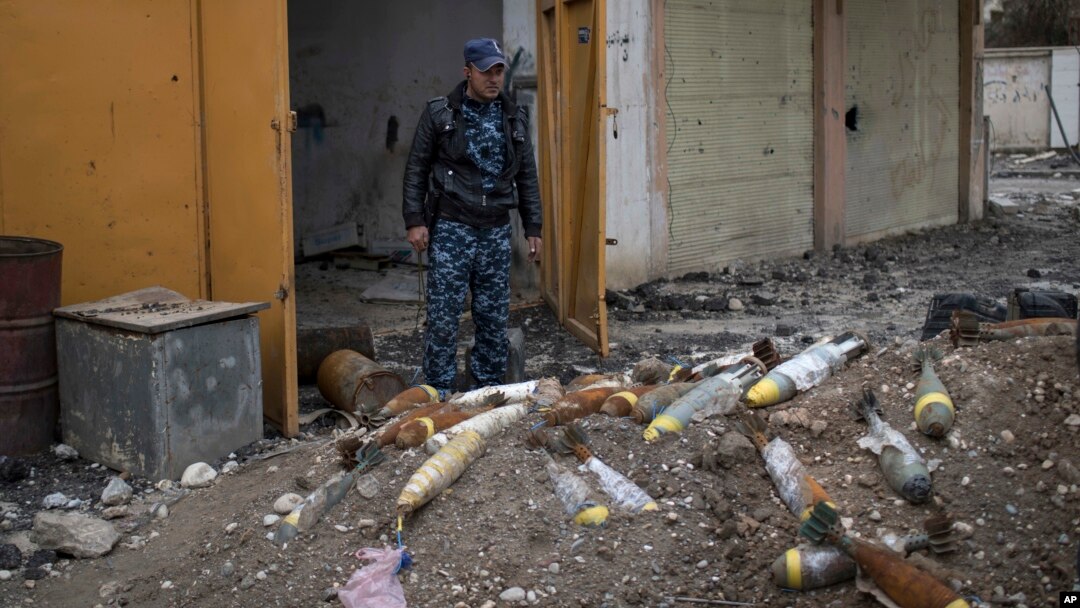 FILE - A member of the Federal Police stands next to unexploded bombs left by Islamic State group militants on the western side of Mosul, Iraq, March 22, 2017.