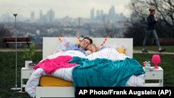 Sepasang suami istri berbaring di tempat tidur dalam sesi foto yang diselenggarakan oleh Yayasan Kesehatan Mental untuk merayakan Hari Tidur Sedunia di Parliament Hill, London, 15 Maret 2018. Hari Tidur Sedunia bertujuan meningkatkan kesadaran pentingnya tidur untuk kesehatan mental. (AP Photo/Frank Augstein)