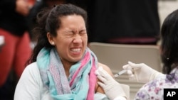 FILE - Ana Farfan reacts to getting an influenza vaccine shot at Eastfield College in Mesquite, Texas, Jan. 23, 2020.