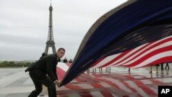 An American flag is unfurled in Paris during a commemoration to mark the 10th anniversary of the Sept. 11 attacks on the United States, at the Trocadero plaza , near the Eiffel tower, Sunday, Sept. 11, 2011.