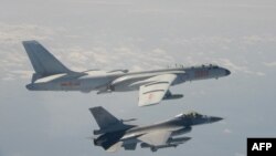 FILE - A Taiwanese F-16 fighter jet flies next to a Chinese H-6 bomber, top, in Taiwan's airspace, in this handout photo taken and released on February 10, 2020, by Taiwan's Defence Ministry.