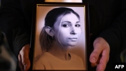 FILE - A colleague of Ukrainian journalist Victoria Roshchyna holds a photograph of her during an event to honor her at a makeshift memorial for fallen Ukrainian soldiers, at Independence Square in Kyiv, on Oct. 11, 2024.