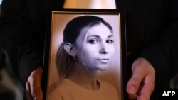 A colleague of Ukrainian journalist Viktoria Roshchyna holds a photograph of her during an event in honor of Viktoria's memory at a makeshift memorial for fallen Ukrainian soldiers, at Independence Square in Kyiv, Oct. 11, 2024. 