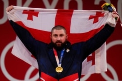 Lasha Talakhadze of Georgia holds his national flag as he celebrates the gold medal he won at the men's +109kg weightlifting event, at the 2020 Summer Olympics in Tokyo, Japan, Aug. 4, 2021.